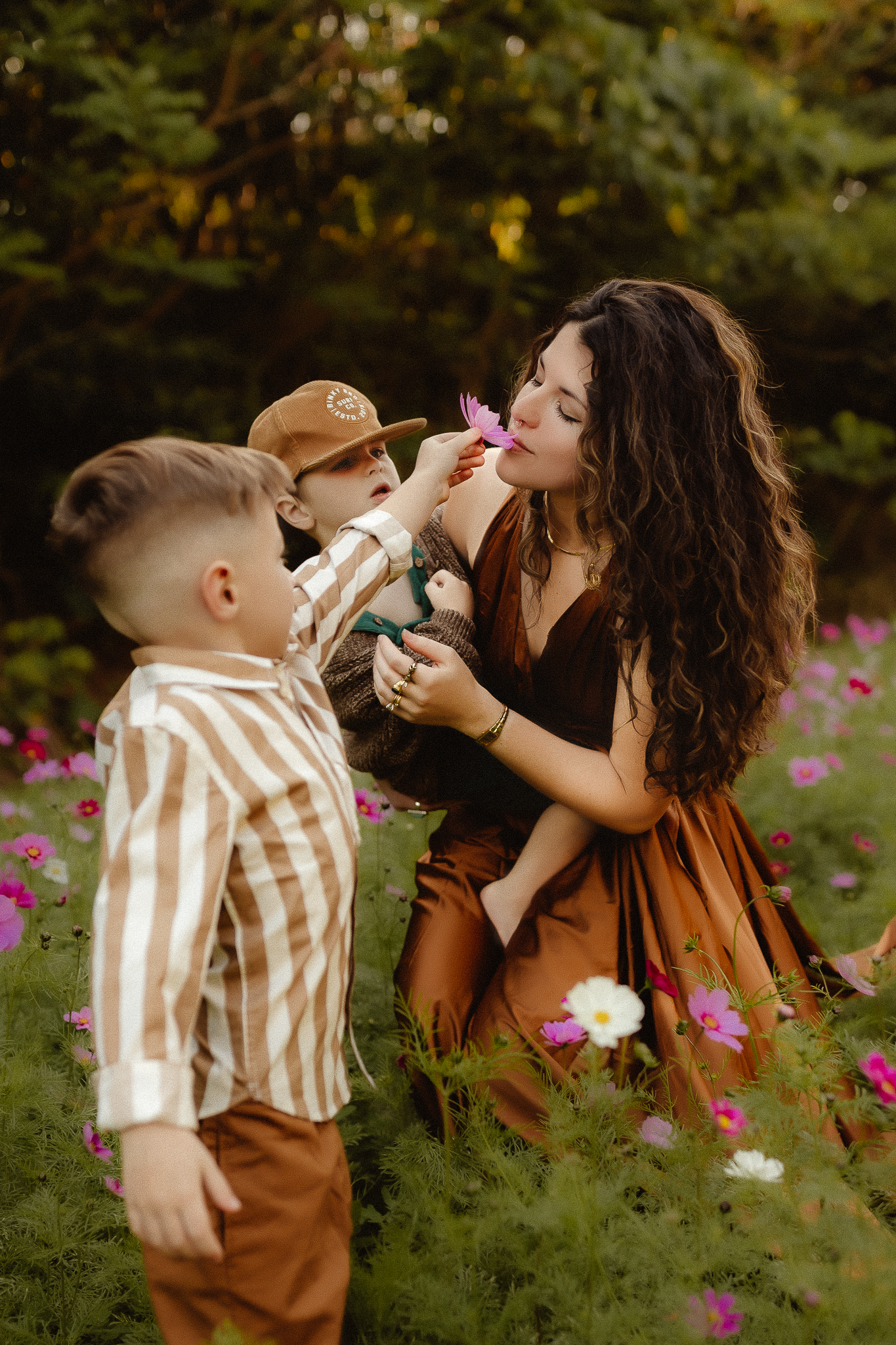 mother and her two sons in a vibrant flower field, one son tenderly offering a bloom to her nose, creating a heartwarming moment being photographed by a Washington Family Photographer