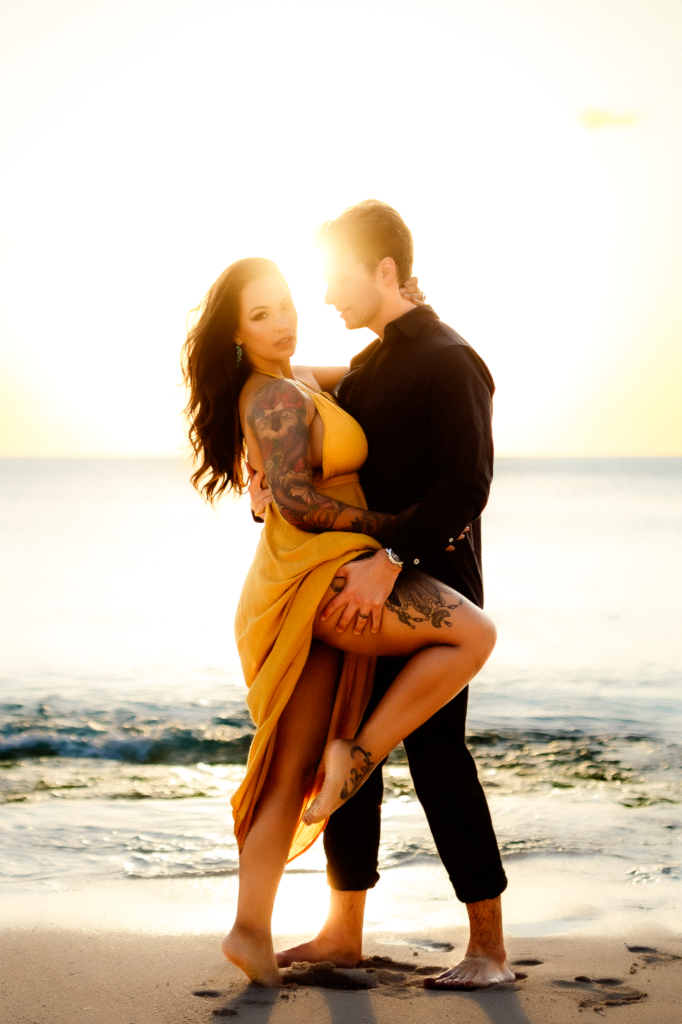 on a washington beach, the couple embraces the allure of the moment. The wife gazes directly with a captivating sultry expression, adding a touch of allure to the scenic coastal backdrop being photographed by a washington photographer