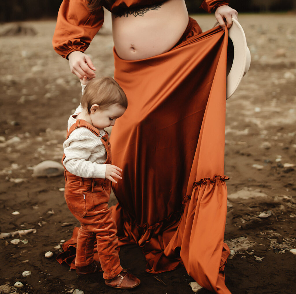pregnant mom is walking her son and holding his hand being photographed by a washington state maternity photographer