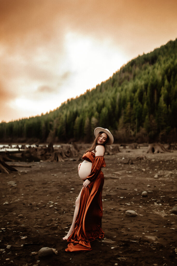 a pregnant momma is embracing her bump while being photographed by a washington state photographer