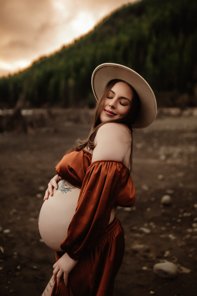 a pregnant momma is embracing her bump while being photographed by a washington state photographer